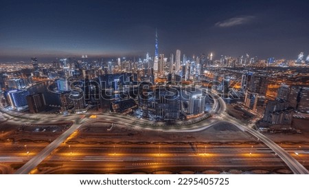 Panoramic skyline of Dubai with business bay and downtown district day to night . Aerial view of many modern skyscrapers with traffic on al khail road after sunset. United Arab Emirates.