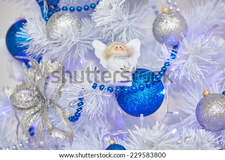 Christmas toys in the form of an angel hanging on the tree next to the balls and beads