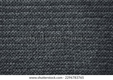 Black striped knitted fabric. Dark knitted texture background.