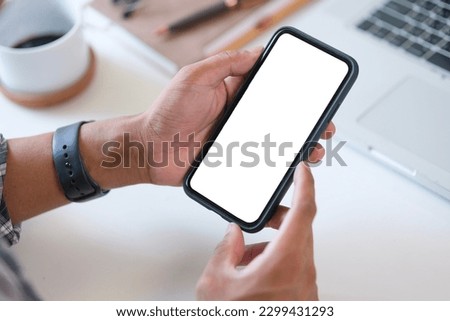 Closeup view of man hands holding smartphone with white empty screen.