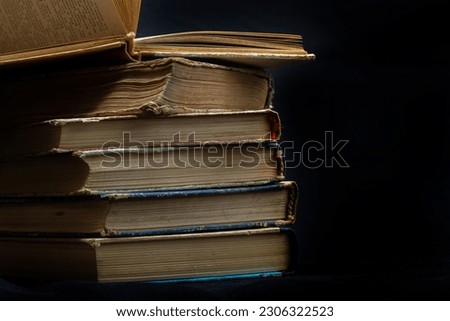 Stack of hardcover old books with an open book on a dark background. Bookshelf shop, Knowledge publications, literature. Bookish bookstore bookstore.