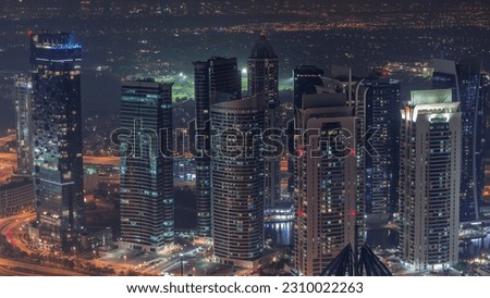 JLT skyscrapers near Sheikh Zayed Road night aerial timelapse. Illuminated residential buildings and skyline with villas