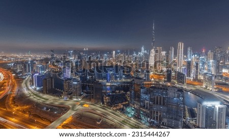 Panoramic skyline with modern architecture of Dubai business bay and downtown towers day to night transition . Aerial view with canal and construction site after sunset