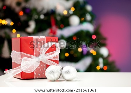 Close up of a Christmas decoration balls and gift box - christmas tree in the background.