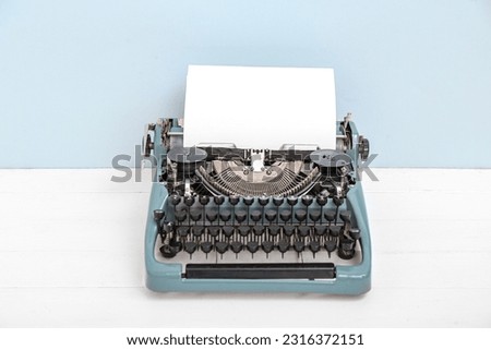 Vintage typewriter on white wooden table near grey wall
