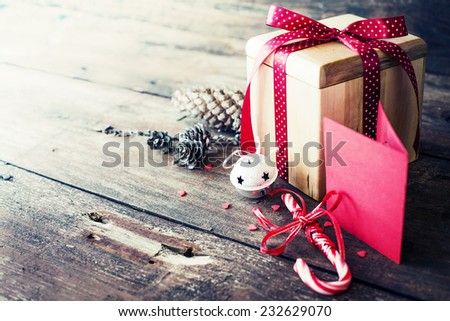 Christmas present with red ribbon on dark wooden background in vintage style / Selective focus
