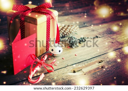 Christmas present with red ribbon on dark wooden background in vintage style / Selective focus