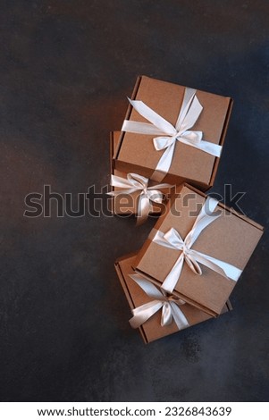 Cardboard boxes on a dark background. Gift delivery. The cardboard holiday box is tied with a ribbon. Festive packaging.Flat lay. Top view. Copy space.