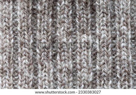 Close-up of a fragment of a cashmere knitted sweater. Natural gray wool textile background from knitted stripes. Warm knitted cozy clothes. Flat lay, macro, top view, mockup
