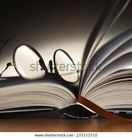 Close up detail of reading glasses on the book