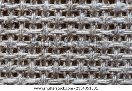 Close-up of linen canvas for hand cross stitch or other embroidery. Gray natural textile background of interwoven threads with square cells. Basis for needlework and hobbies. Flat lay, macro, mockup