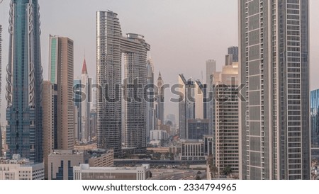 Futuristic towers and skyscrapers with traffic on streets in Dubai Downtown and financial district after sunset. Urban city skyline aerial day to night transition timelapse from above