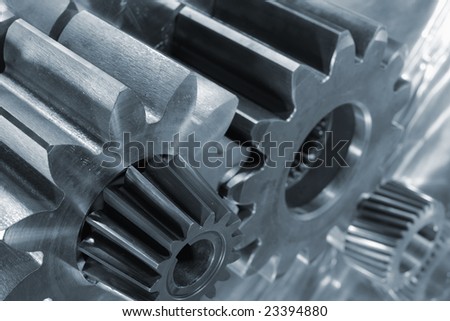 four differant titanium gears, pinions, against brushed aluminum background, blue toning concept