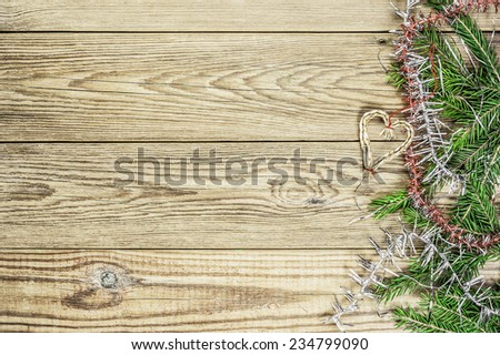 Fir branches and heart toy on a wooden background