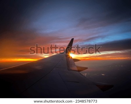 Point of View: Airplane passenger viewing sunrise or sunset over the wing of a passenger commercial airplane. 