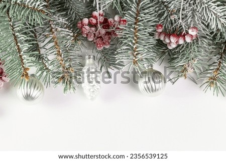 Christmas card with fir branches, viburnum berries covered with hoarfrost, and Christmas decorations. Copy space.
