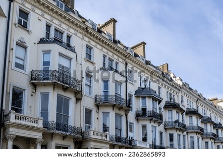 Row of grand ornate vintage townhouses with metal balconies, bay windows and porticos with Corinthian columns in an English town