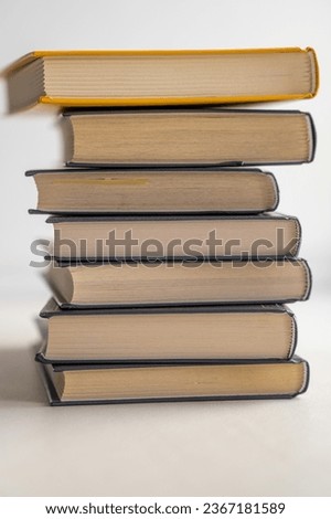 Stack of books on a white background. One book is yellow. Book reading and learning concept.