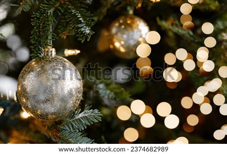 Gold ornament ball close up on the christmas tree with bokeh lights in the background. Christmas and New Year concept.