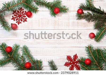 Christmas background - fir branches and red decorations on a white wood table. Flat layout, top view composition border with copy space.
