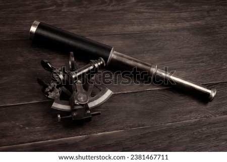 Retro vintage spyglass telescope with sextant on wooden background