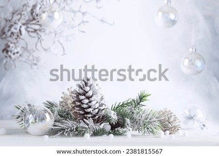 Christmas still life with snowy pine cones, baubles and  fir branches on light background. Winter or Christmas festive concept.