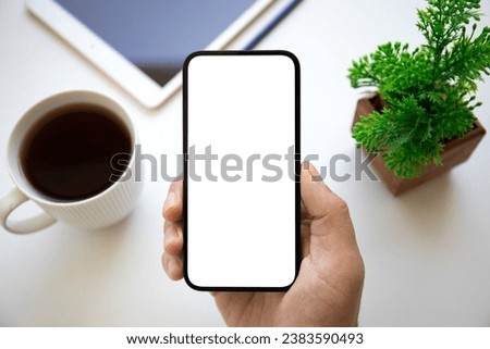 man hand holding phone with isolated screen background of table in office