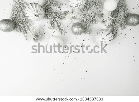 Christmas composition, white and silver decorations, fir tree branches, white flowers, silver stars confetti on white background. Christmas, New Year, winter concept. Top view, flat lay, copy space. 