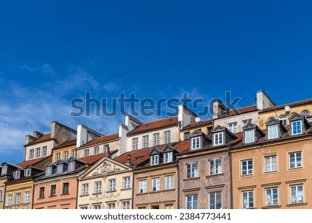 Colorful facades and tiled rooftops of old townhouses in the Old Town Market Square (Rynek Starego Miasta) in Warsaw, Poland, with blue sky in the background, copy space.