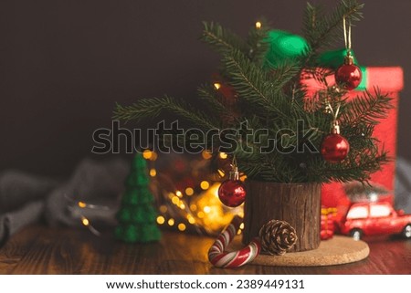 Red toys on the Christmas tree. Christmas cozy composition. Christmas tree branches on a dark background, decorated with red toys and garlands. Christmas lights.