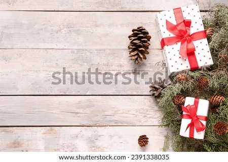 Christmas composition with branches, pine cones and gift boxes on light wooden background