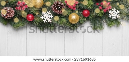 Christmas tree branch decorated with golden and green balls, red berriesand snowflakes on white wooden background. Top view, flat lay with copy space, banner, header, New Year background	