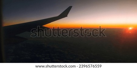 View from the airplane window at a beautiful sunset  and the airplane wing. Red sky as seen through window of an airplane.