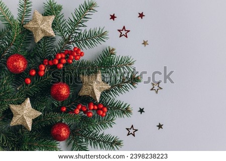 Spruce branch with golden stars, balls and red berries on a grey background. Flat lay. Place for text.