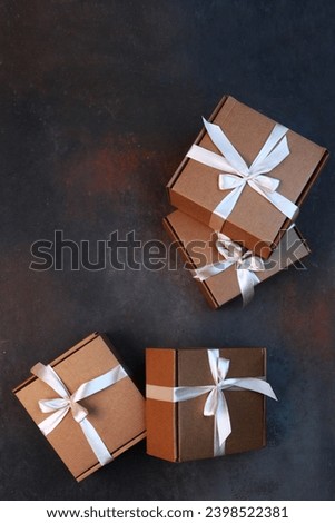 Gift for holiday. Cardboard boxes on dark background. Gift delivery. Cardboard holiday box is tied with ribbon. Festive packaging. With space to copy. View from above.