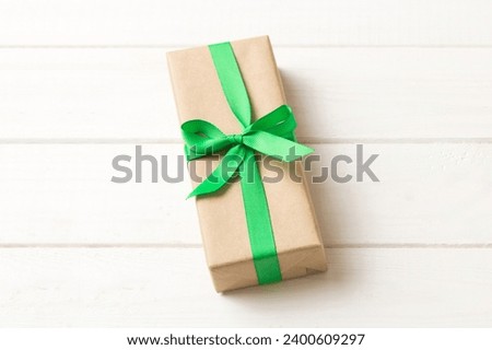 Wrapped christmas or other holiday handmade present in craft paper with colored ribbon. Present box, decoration of gift on table, top view with copy space.