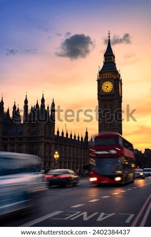 Public transportation bus and cars on asphalt road near Big Ben or Clock Tower under picturesque sky in dusk in London city at night