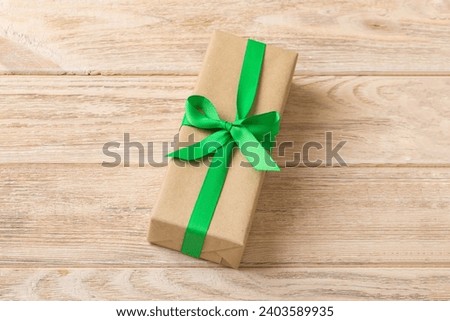 Wrapped christmas or other holiday handmade present in craft paper with colored ribbon. Present box, decoration of gift on table, top view with copy space.