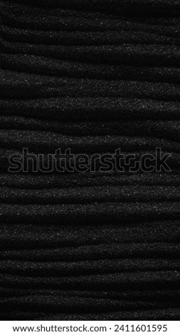 Dark black sand. Stripes and ripples of smooth volcanic sand texture or wallpaper. Wave pattern in black sand background.