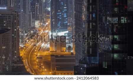 Aerial view from above to a busy road junction in Dubai during all night timelapse. Cars driving straight forward in both directions. Business bay district with tall towers