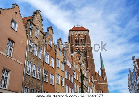 Basilica St. Mary's church tower over Piwna street. Historic cityscape view of brick gothic church and colourful historic buildings in old town Gdansk, Poland. Bazylika Mariacka. 