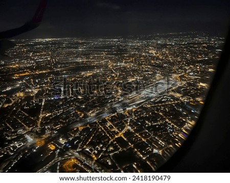 The city of Rome at night, with numerous lights, visible from the airplane window.