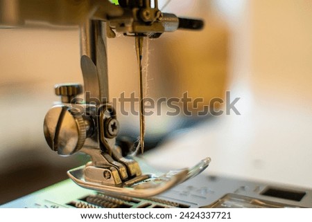 Sewing machine needle with thread, close-up on a blurred background