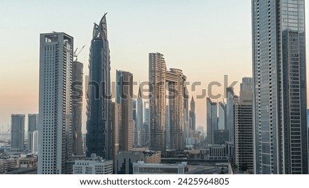 Futuristic towers and skyscrapers cityscape with traffic on streets in Dubai Downtown and financial district. Urban city skyline aerial night to day transition timelapse before sunrise.
