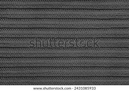 Jersey textile background , black striped knitted fabric. Woolen knitwear, sweater, pullover surface texture, textile structure, cloth surface, weaving of knitwear material. Wallpaper, backdrop.