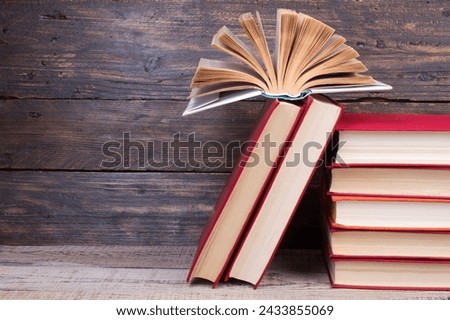 Composition with hardback books, fanned pages on wooden deck table and background. Books stacking. Back to school. Copy Space. Education background