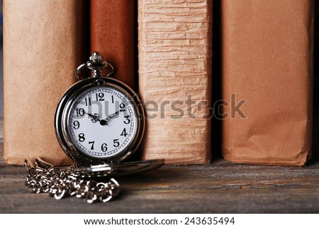 Silver pocket clock on books background