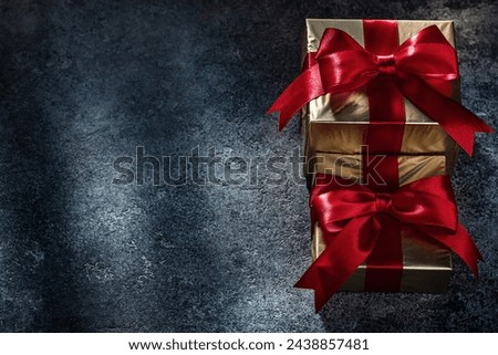 Two Gold Giftboxes With Red Bows On Dark Background