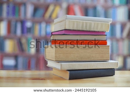 stack of books on wooden table in library background