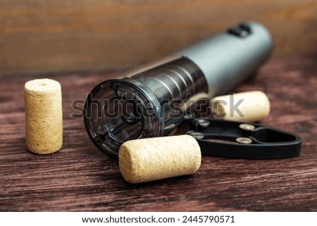 electric corkscrew and wine bottle caps lie on a dark wood table preparing for the holiday.